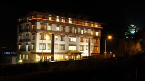 Et hotel med flere etager, oplyste vinduer og et godt belyst indgangsparti.