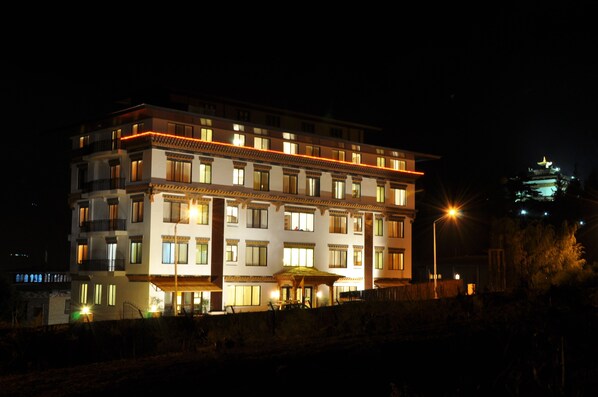 A multi-story hotel with illuminated windows and a well-lit entrance area.
