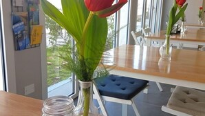 A dining area with a table, chairs, and a vase with a red flower. - Alba Hotel (Ravenna)
