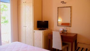A hotel room with a bed, a TV on a stand, a desk with a chair, a mirror, and a wardrobe. - Alba Hotel (Ravenna)