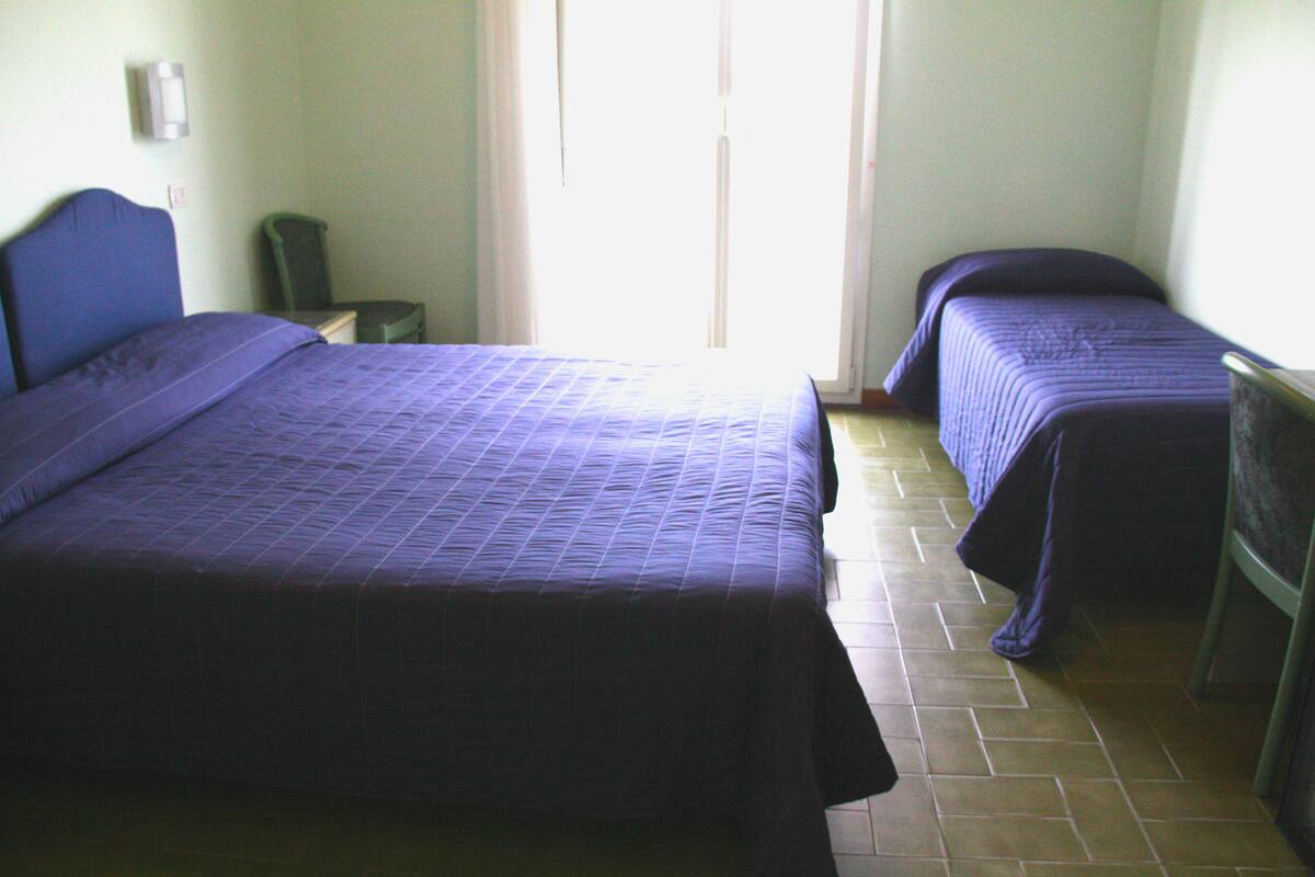 Una habitación con dos camas, una silla y una mesita.