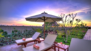 A rooftop terrace with lounge chairs, an umbrella, and a view of the sunset. - Ry's Lotus Resort d'Angkor (Siem Reap)