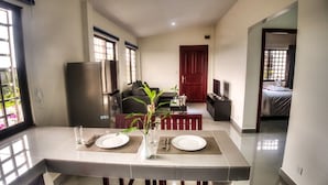 A modern kitchen with a dining area, a refrigerator, and a dining table set for two. - Ry's Lotus Resort d'Angkor (Siem Reap)