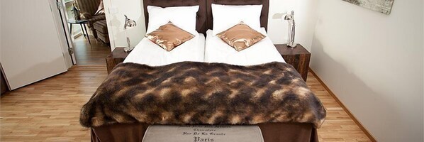 A bed with a fur throw, two pillows, and a nightstand with a lamp.