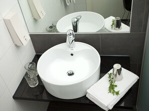 A bathroom with a white sink, a mirror, and a black countertop.
