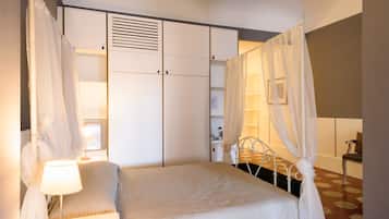 A bedroom with a bed, a nightstand, a lamp, a wardrobe, and a chair.