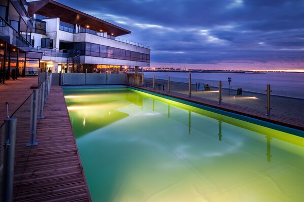 A modern building with a pool and a view of the water.