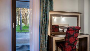 Une chambre d’hôtel équipée d’un bureau, d’une chaise et d’une grande fenêtre avec des rideaux.