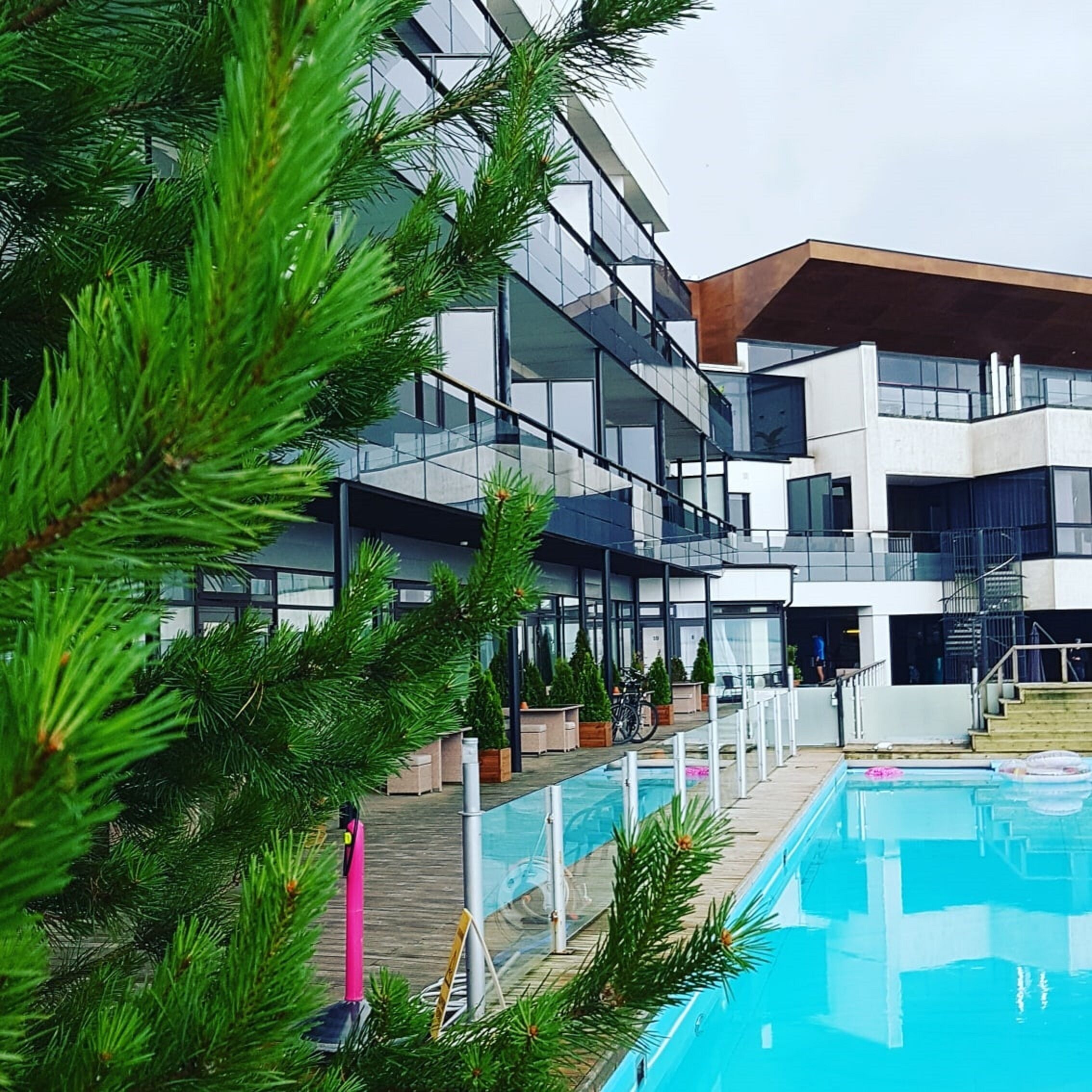 Un edificio moderno con piscina, rodeado de vegetación.