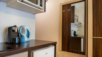 A kitchenette with a coffee maker, a kettle, and a microwave.