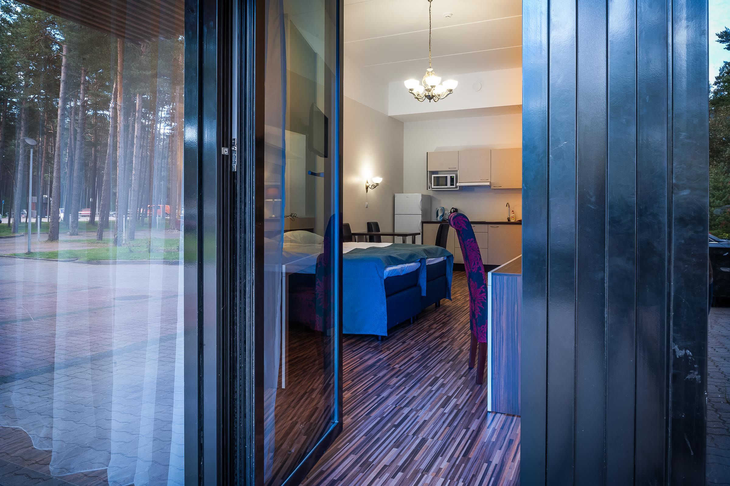 Une chambre moderne dotée d’une porte vitrée donnant sur un coin repas, d’une petite kitchenette et d’un espace salon avec un canapé bleu.