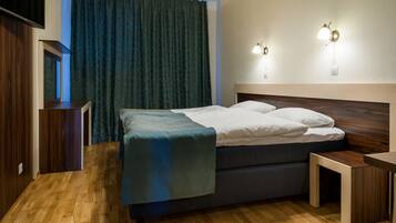 A neatly arranged bedroom with a bed, bedside tables, and a TV mounted on the wall.