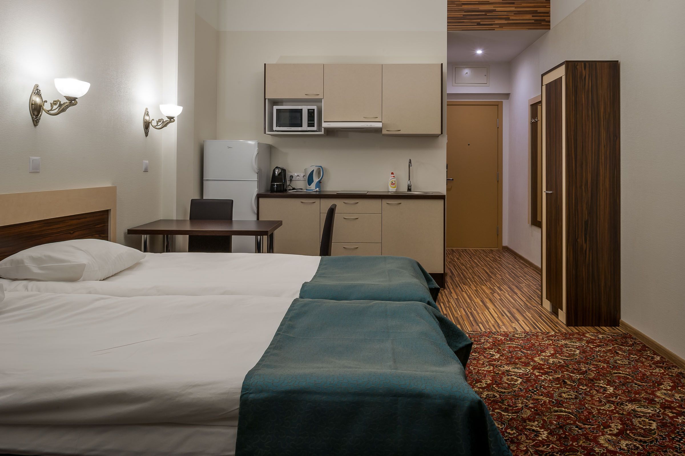 A hotel room with a bed, a desk, a microwave, and a wardrobe.