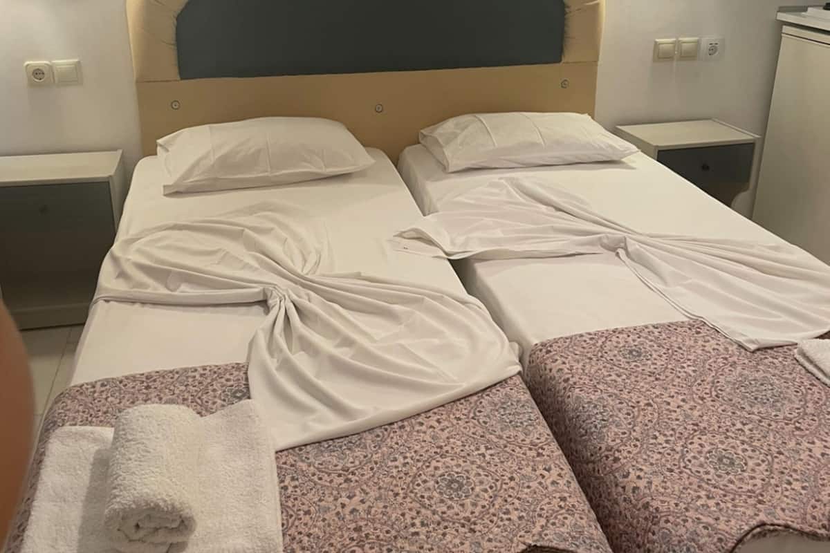 A double bed with a headboard, two bedside tables, and a wall-mounted light fixture.