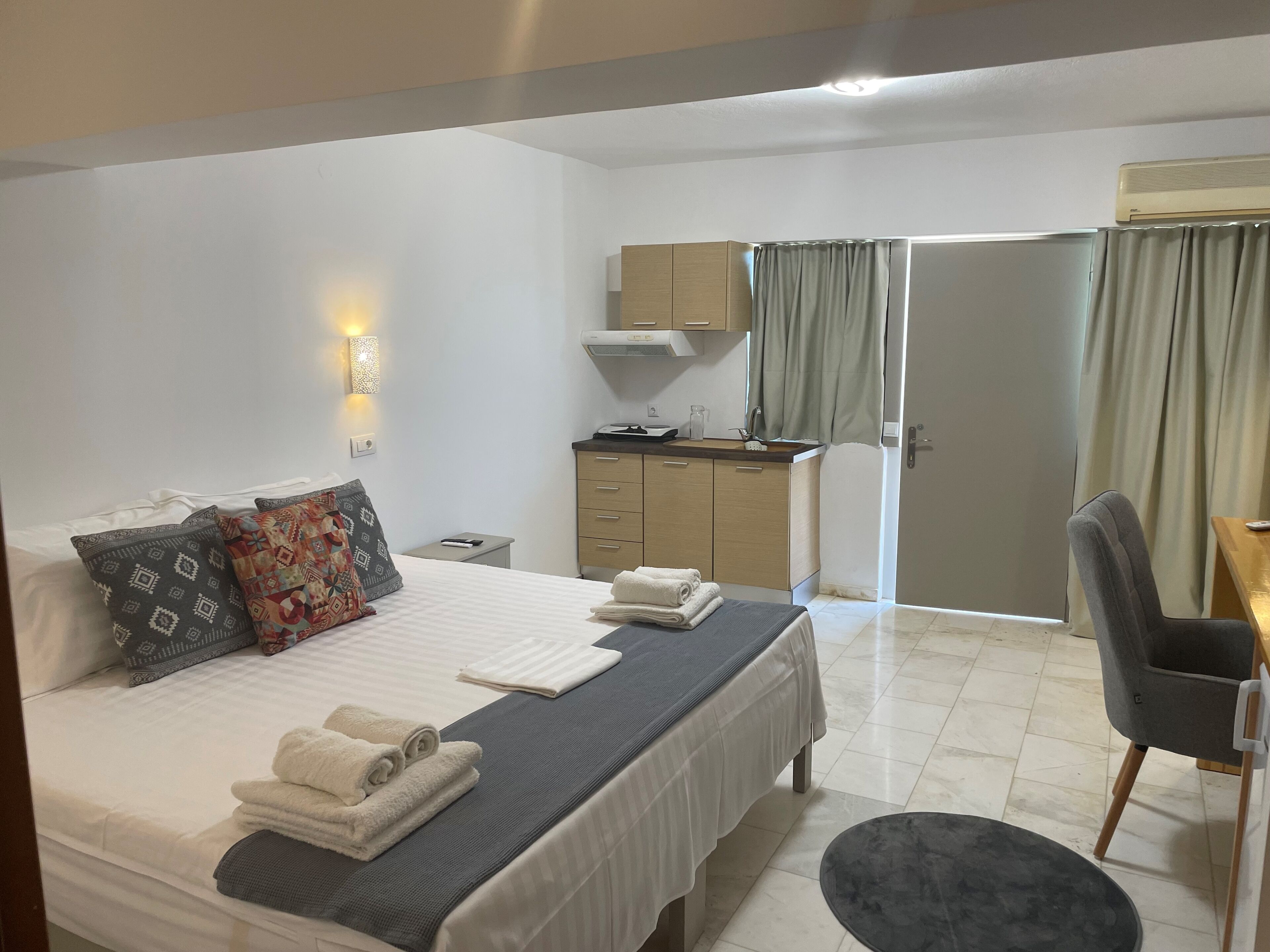 A hotel room with a bed, a desk, a chair, a wardrobe, and a bathroom.