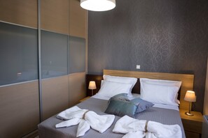 Una habitación de hotel moderna con una cama grande, dos lámparas de noche y vistas a través de un panel de vidrio.