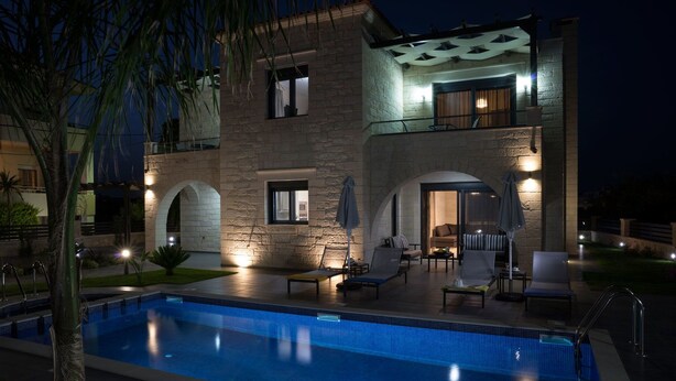 Un edificio de piedra de dos pisos con piscina, mobiliario exterior y un patio cubierto.