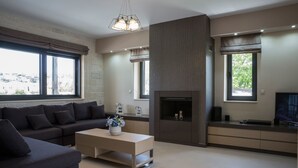 Una sala de estar moderna con sofá, mesa de centro, chimenea, televisor y ventanas amplias.
