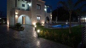 Una casa moderna de dos pisos con piscina, fachada de piedra y zona de estar al aire libre.