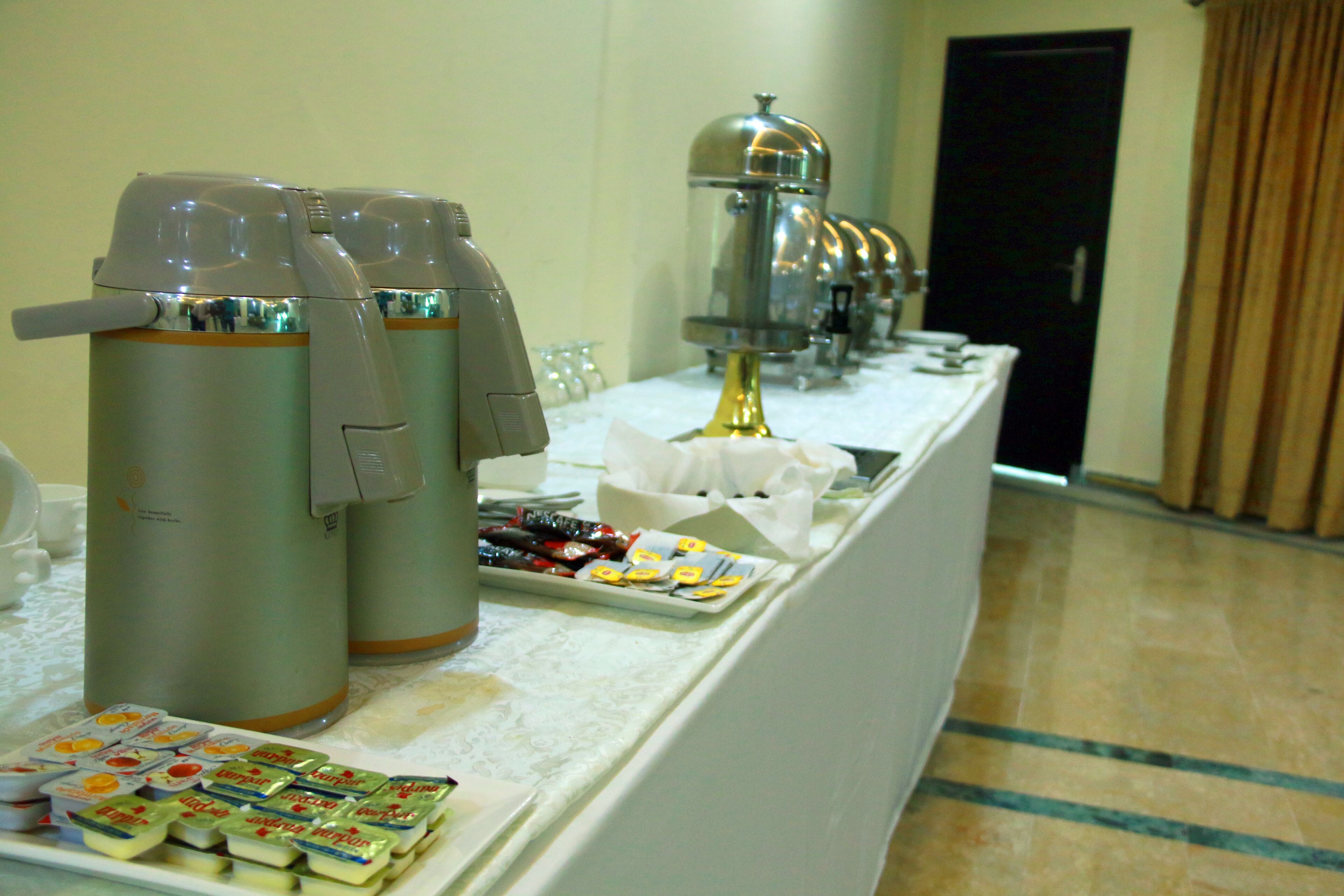 A buffet setup with coffee dispensers, a beverage station, and a variety of food items on a table.