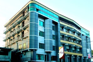A multi-story hotel with balconies, large windows, and a prominent 'Hotel One' sign.