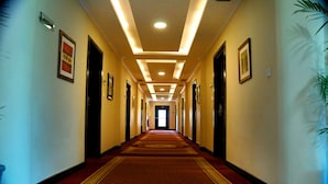 A hotel hallway with a red carpet, framed pictures on the walls, and a ceiling with recessed lighting. - Hotel One Abbottabad (Abbottabad)