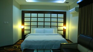 A hotel room with a large bed, two bedside lamps, a sofa, a small table with a tissue box, and a ceiling light. - Hotel One Abbottabad (Abbottabad)
