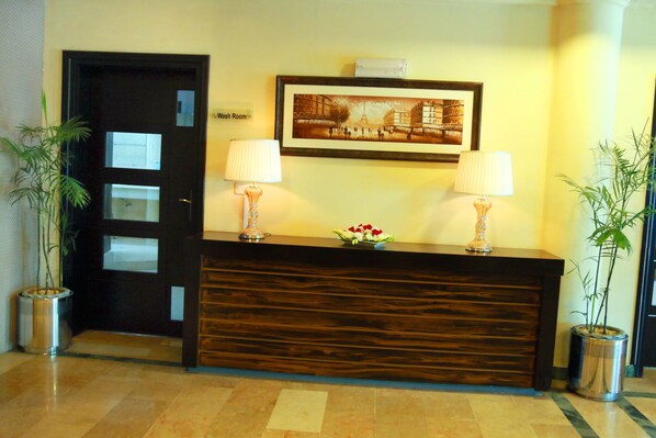 A reception desk with two lamps, a framed picture above, and a sign indicating a wash room.