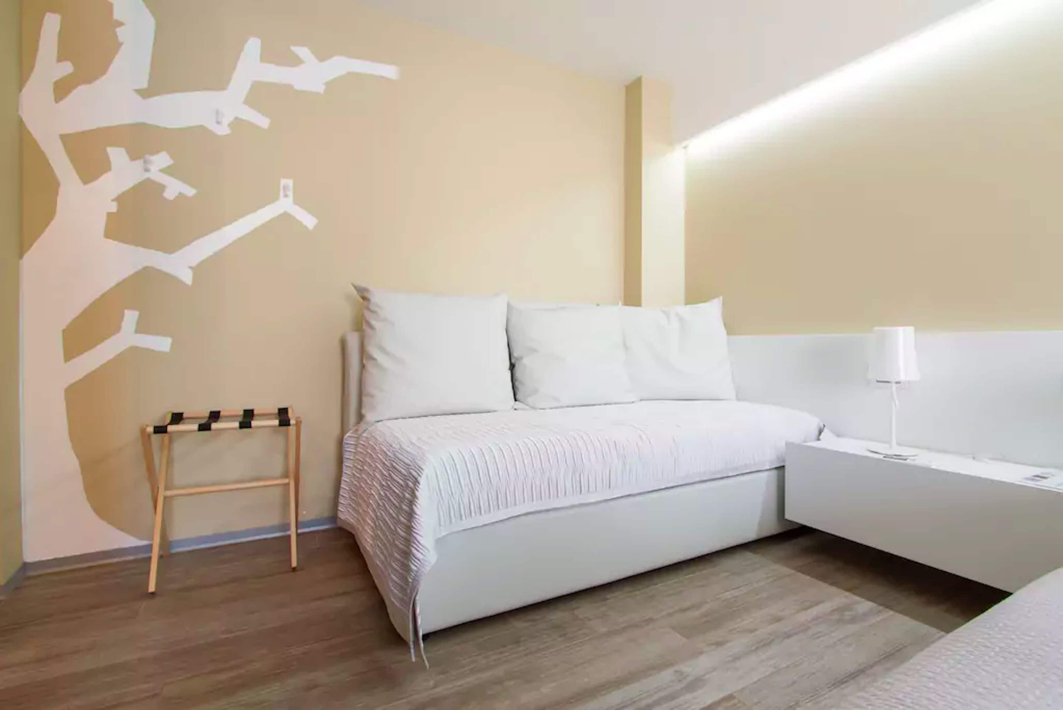 A modern bedroom with a bed, bedside table, and a wall art piece.