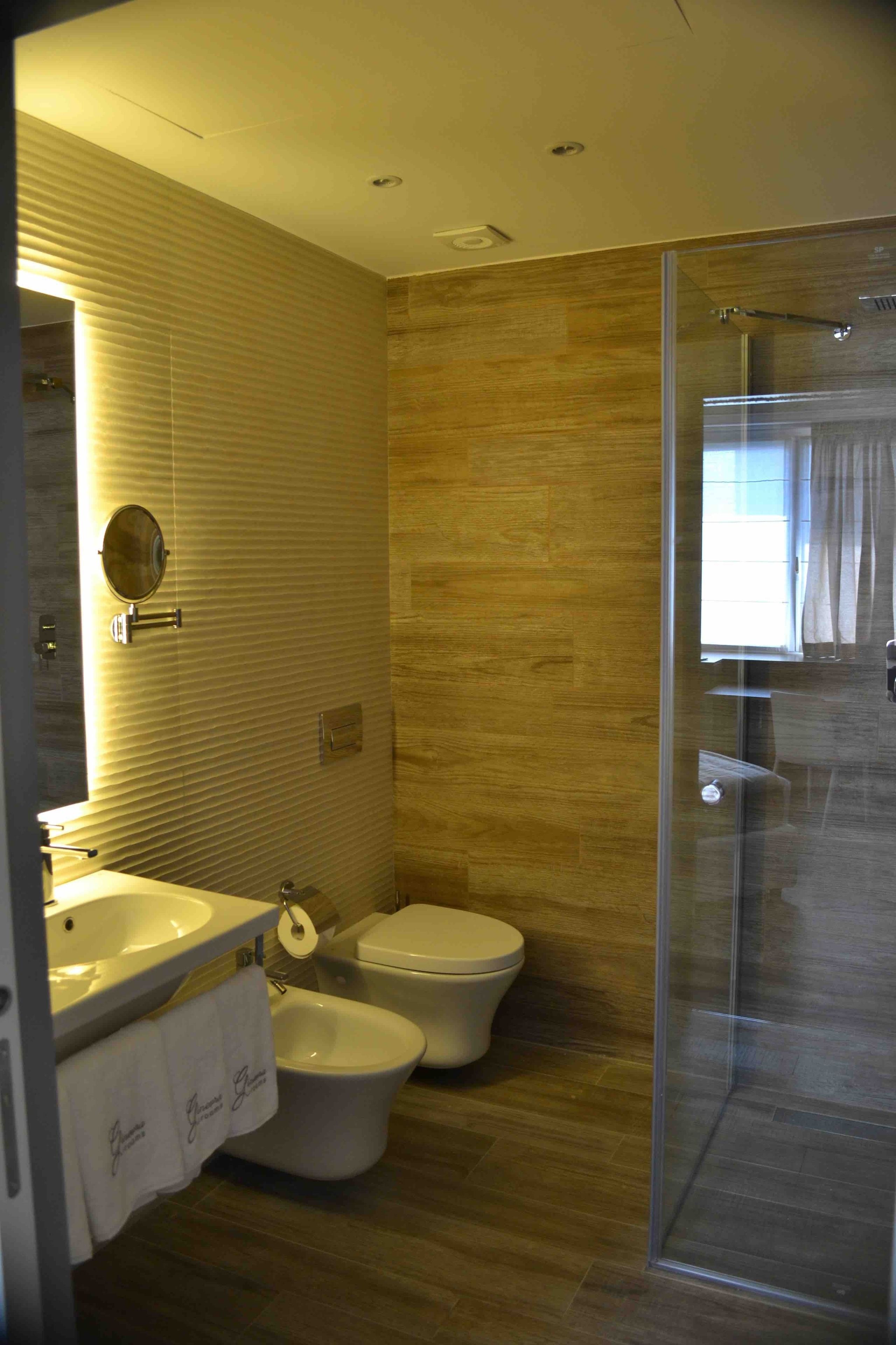Ein modernes Badezimmer mit Duschkabine aus Glas, einem Bidet und einer Toilette.