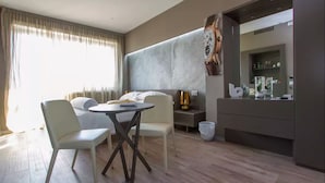 Una habitación de hotel moderna con comedor, un espejo grande y un minibar.