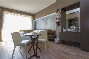 Una camera d'albergo moderna con angolo ristoro, uno specchio grande e un minibar.