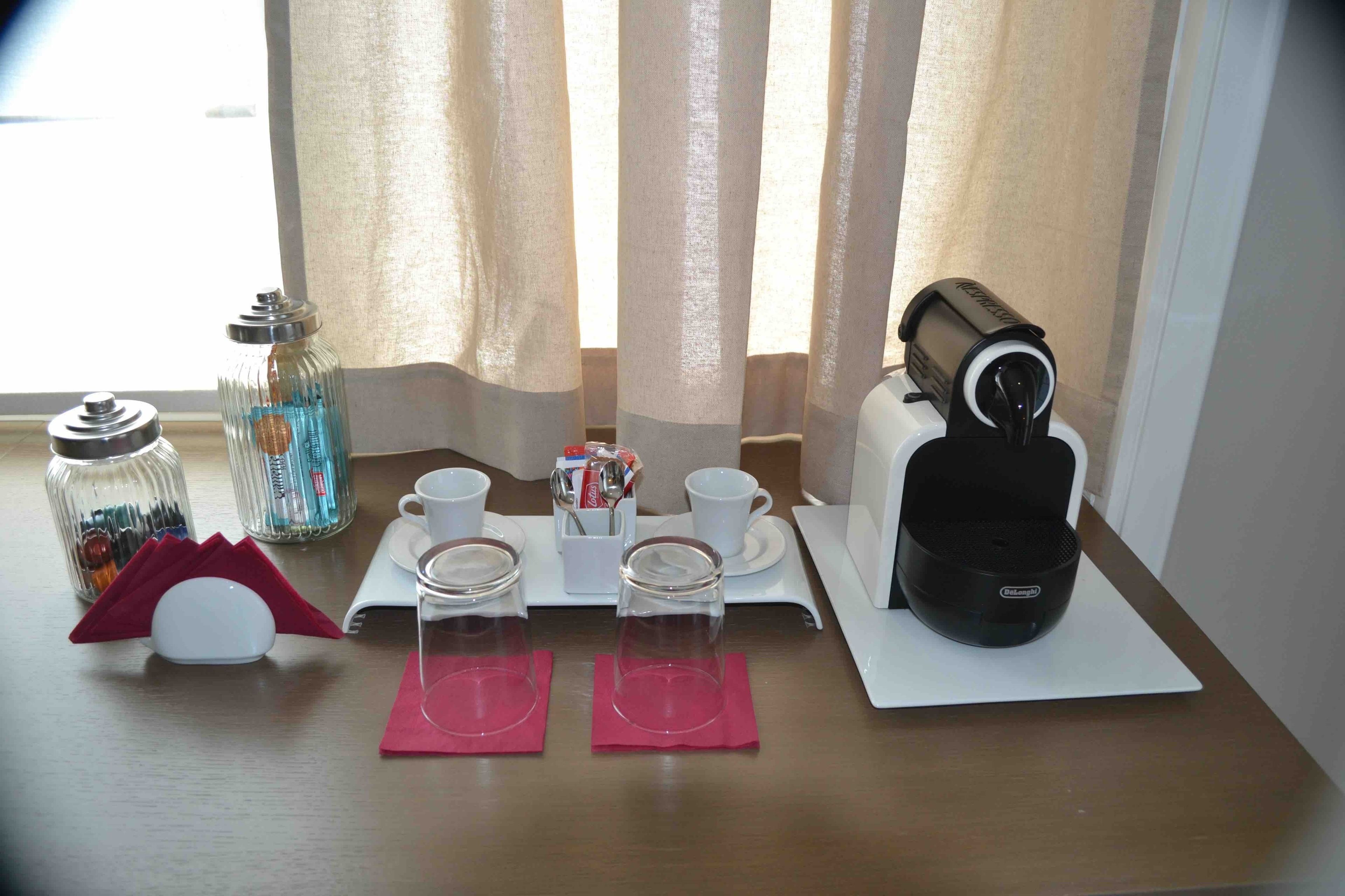 A neatly arranged breakfast setup with a coffee maker, cups, and a sugar container on a table.