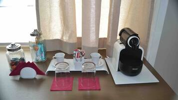 A neatly arranged breakfast setup with a coffee maker, cups, and a sugar container on a table.