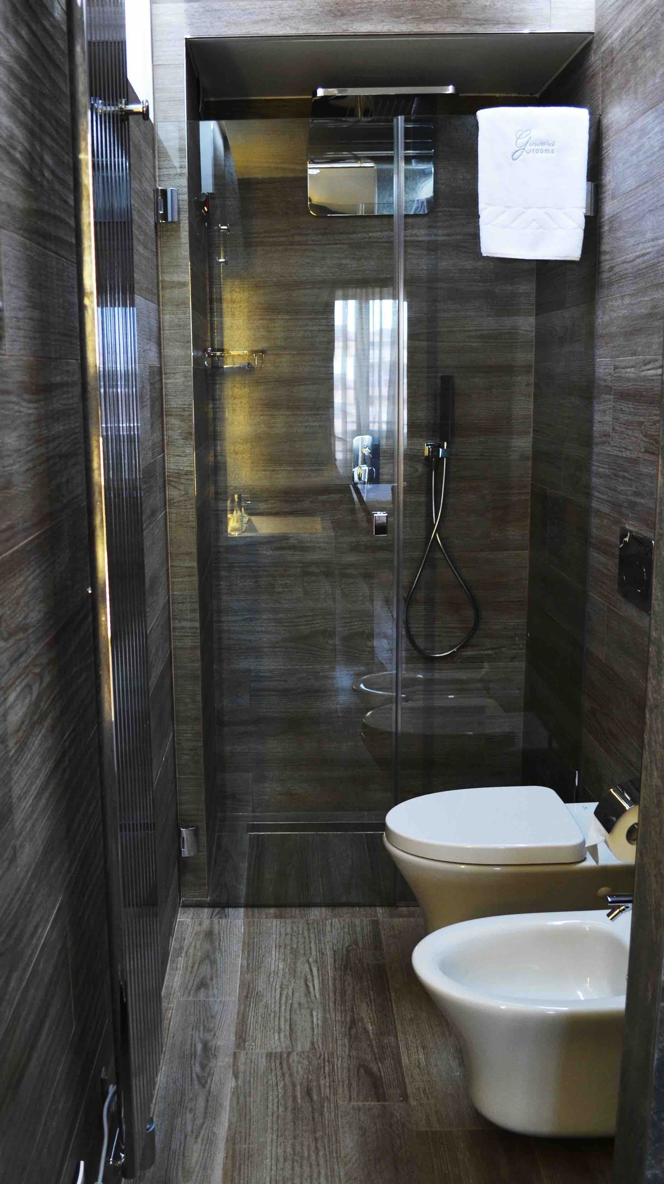 A modern bathroom with a glass-enclosed shower, a toilet, and a bidet.
