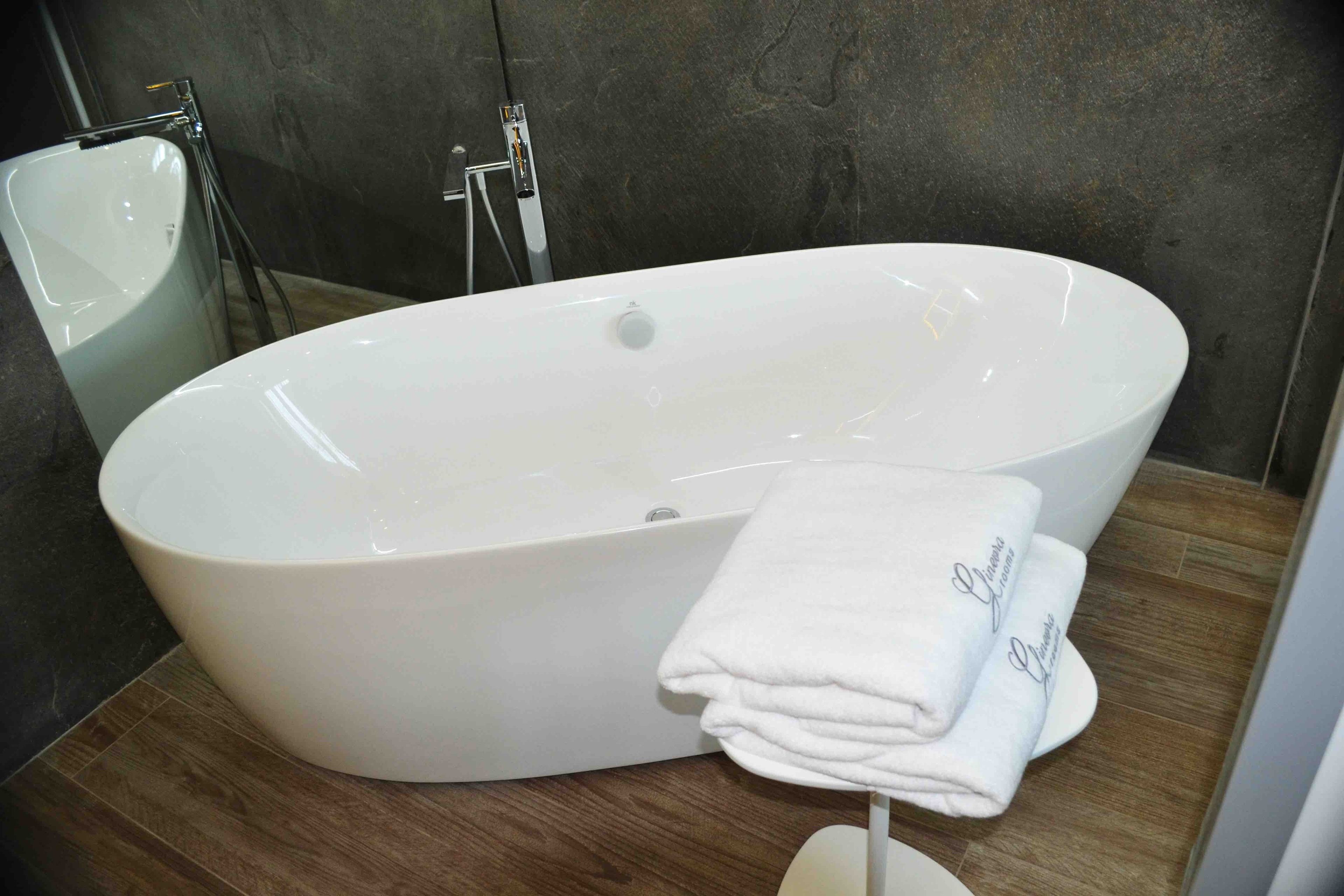 A modern bathroom with a large oval bathtub, a white sink, and a towel rack with folded towels.