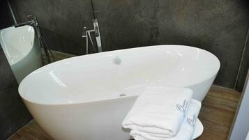 A modern bathroom with a large oval bathtub, a white sink, and a towel rack with folded towels.
