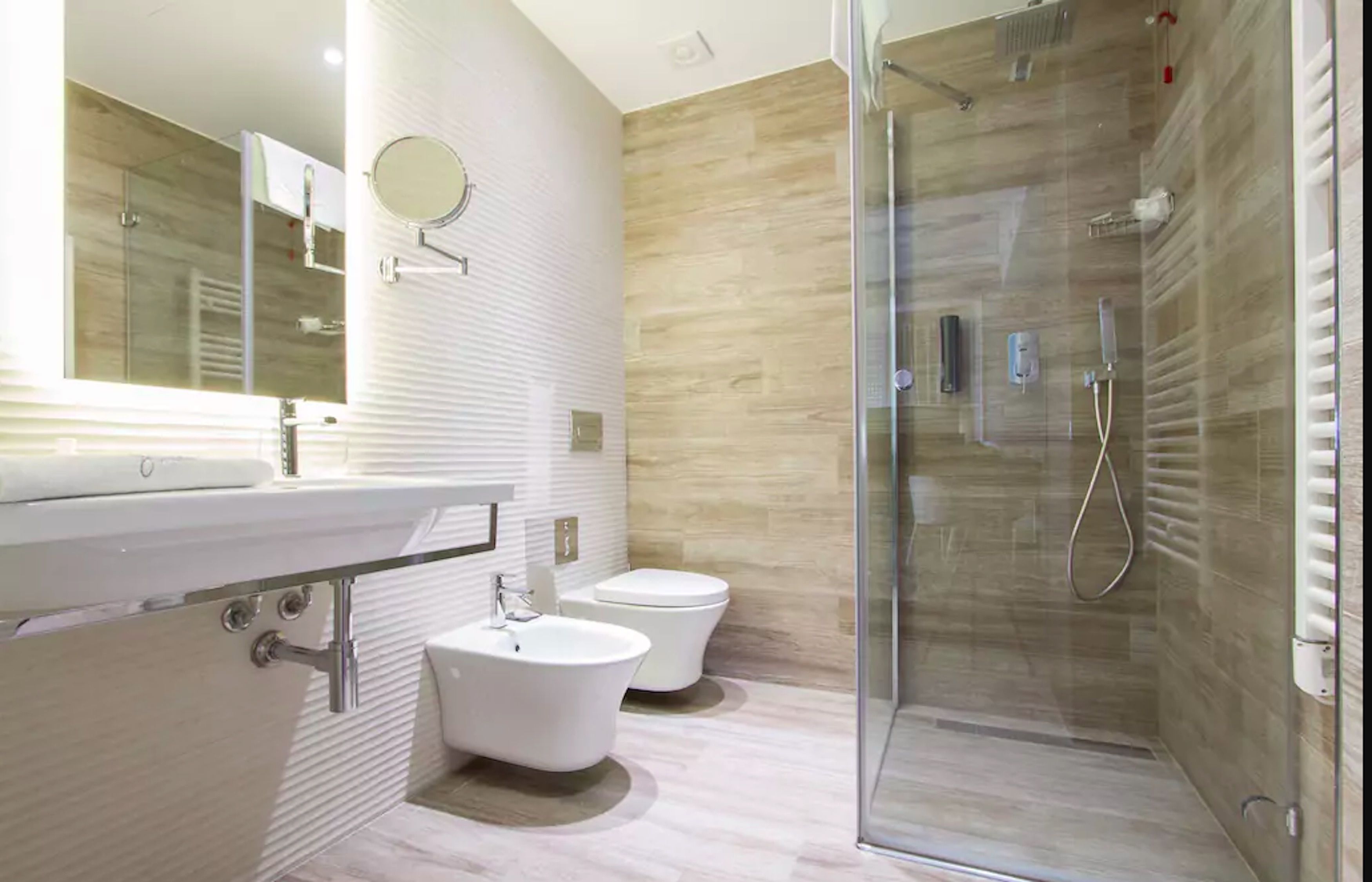 Un baño moderno con ducha envuelta en vidrio, lavamanos e inodoro.
