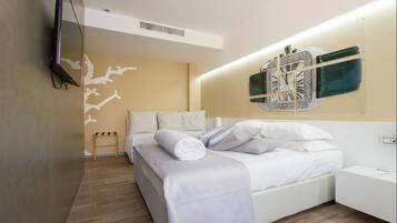 A modern bedroom with a bed, a wall-mounted clock, and a television.
