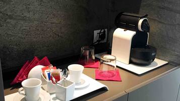 A breakfast setup with a coffee maker, cups, a glass, and a small jar on a tray.