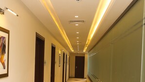 A long, well-lit hallway with doors on one side and a glass wall on the other. - Hotel One Rahim Yar Khan Club Road (Rahim Yar Khan)