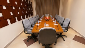 A conference room with a long table, multiple chairs, water bottles, and a floral centerpiece. - Hotel One Rahim Yar Khan Club Road (Rahim Yar Khan)