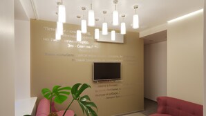 A modern interior with a beige wall, a flat-screen TV, and a potted plant. - Stan Gret Hotel (Kyiv)