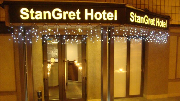 The exterior of StanGret Hotel with a sign above the entrance, a set of double doors, and a small outdoor area with a light fixture. - Stan Gret Hotel (Kyiv)