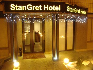 The exterior of StanGret Hotel with a sign above the entrance, a set of double doors, and a small outdoor area with a light fixture. - Stan Gret Hotel (Kyiv)