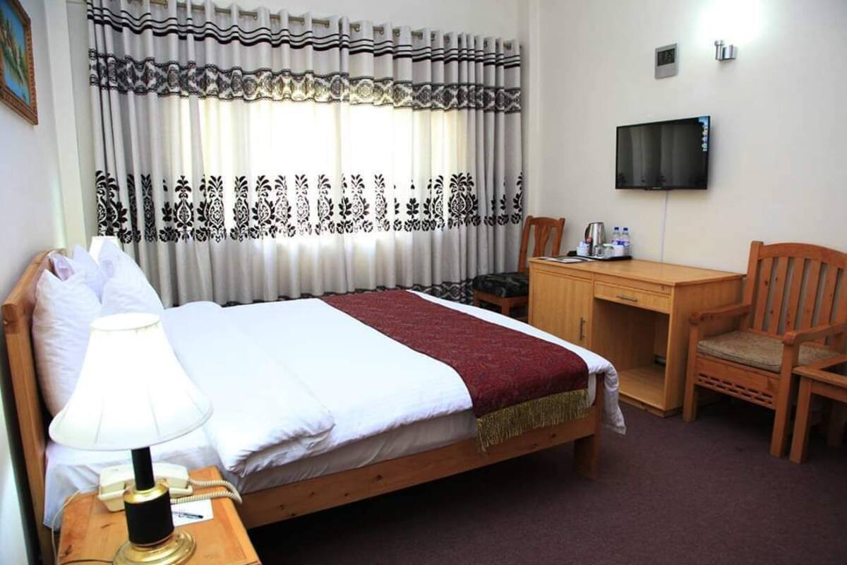 Ein Hotelzimmer mit Bett, Schreibtisch, Stuhl, Fernseher und Lampe.