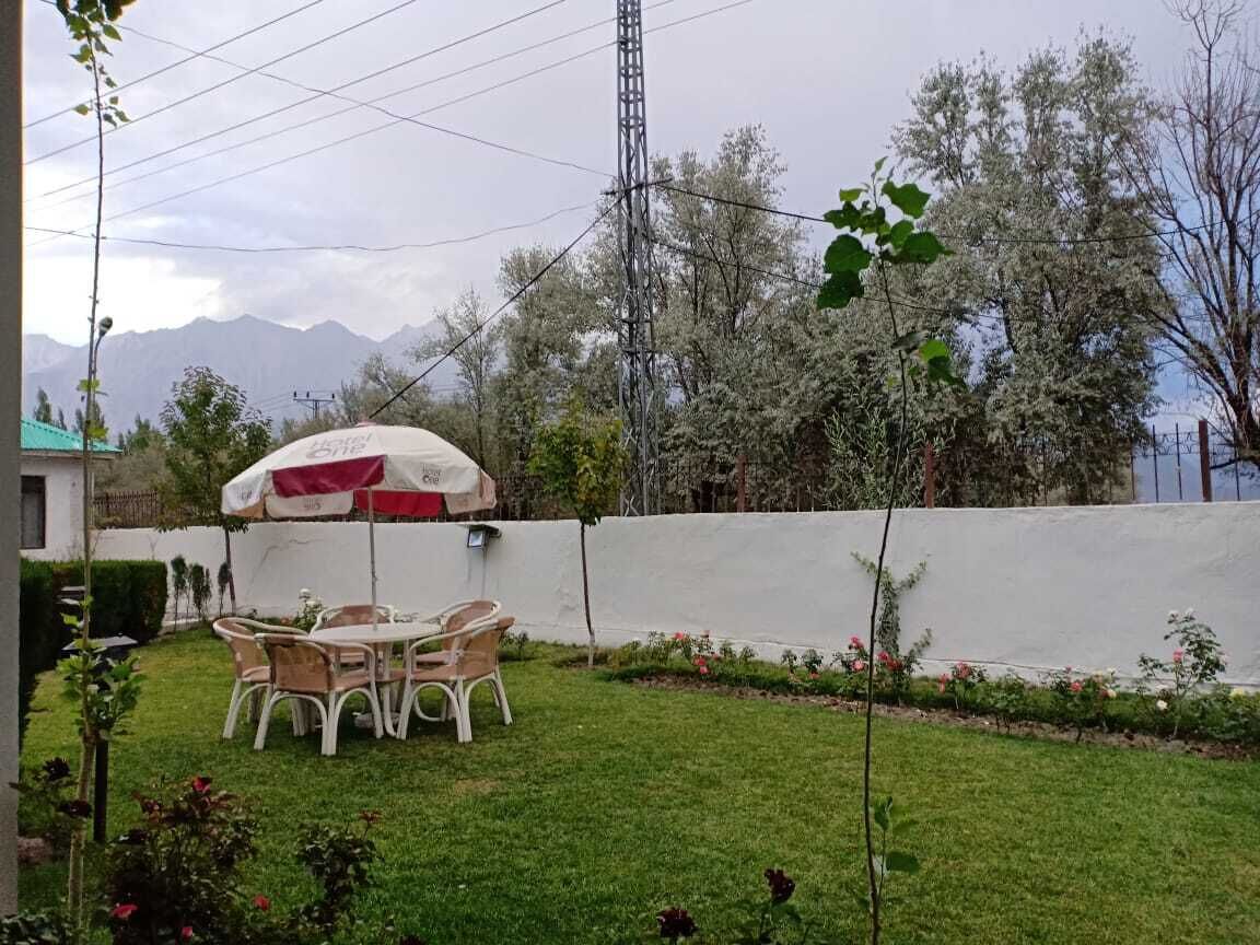 Un patio con mesa y sillas, una pared blanca y vistas a la montaña.