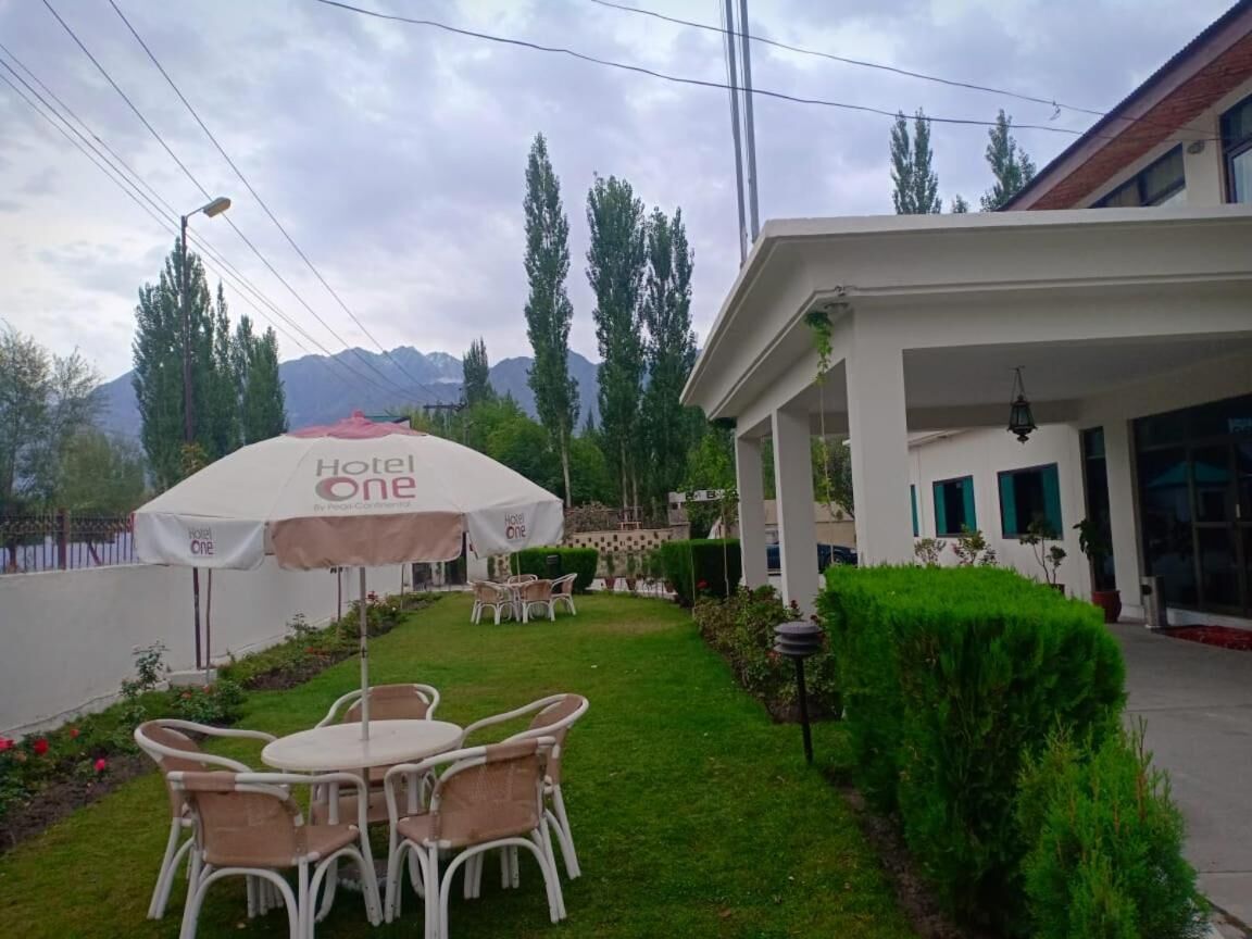 Hotel com área de pátio, mobiliário de exterior e paisagem montanhosa ao fundo.