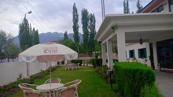 Hotel com área de pátio, mobiliário de exterior e paisagem montanhosa ao fundo.