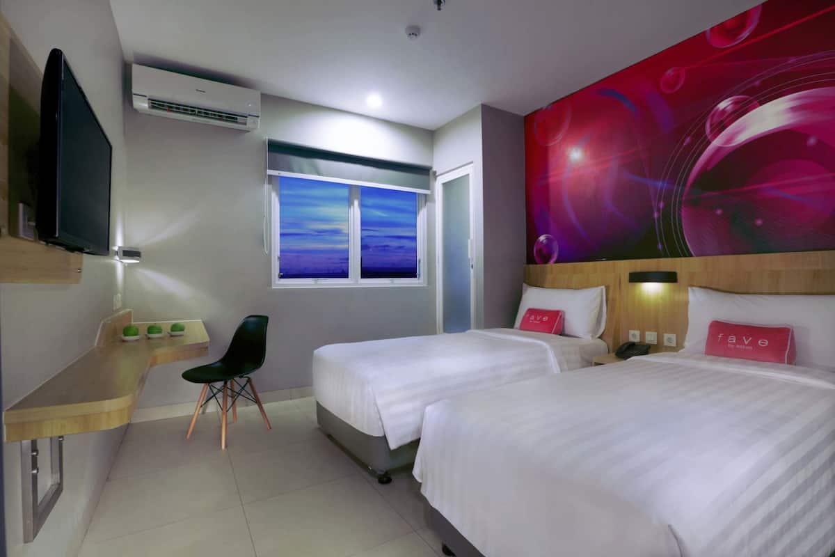 A hotel room with two beds, a desk, a chair, a TV, and a large window with a view.